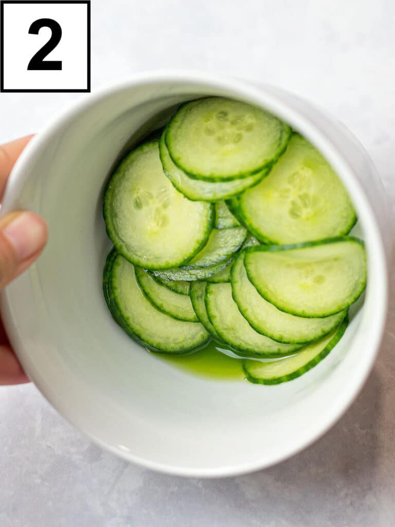 salted cucumber slices in a white bowl