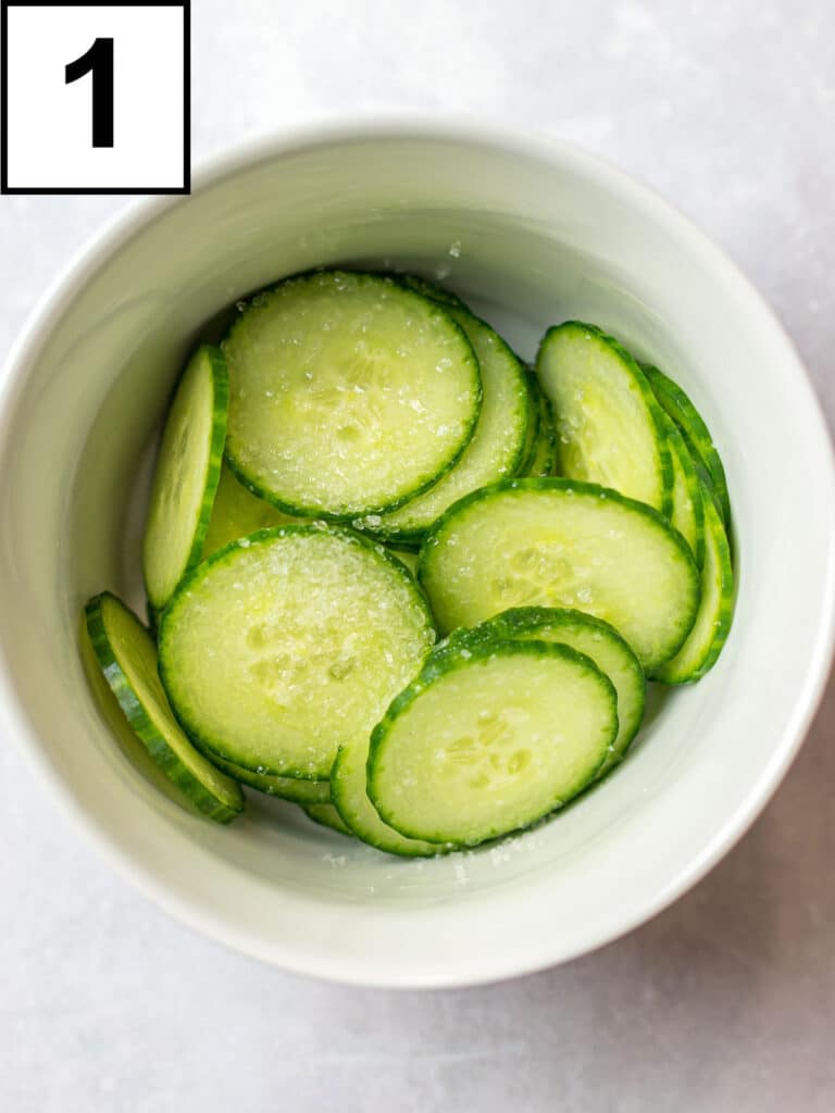 cucumber slices sprinkled with salt in a white bowl