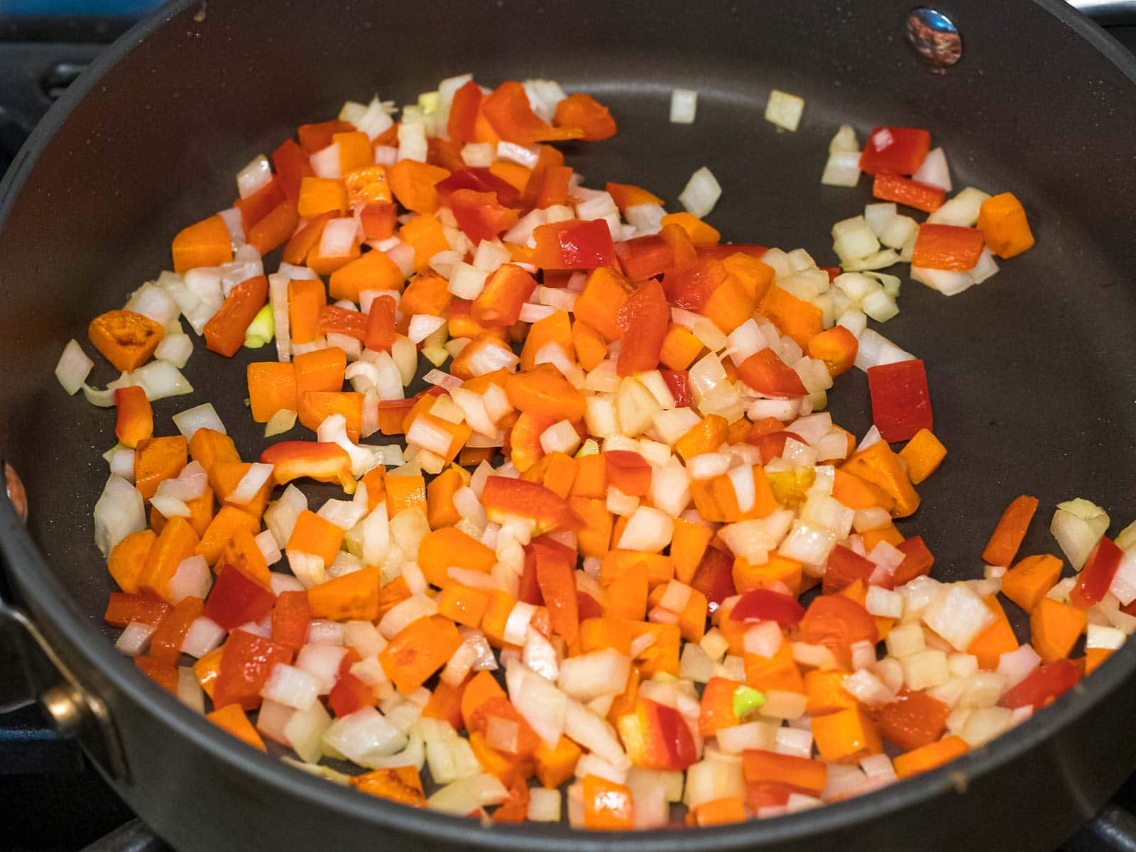 red bell peppers, carrots, and onions stir fried in a pan