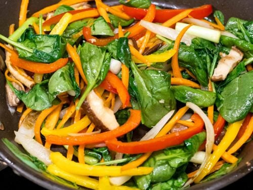 spinach, stir fried carrots, shiitake mushrooms, and bell peppers in a pan