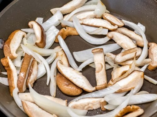 sliced shiitake mushrooms and white onions stir fried in a pan