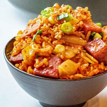 bowl of kimchi fried rice with spam topped with scallions and sesame seeds