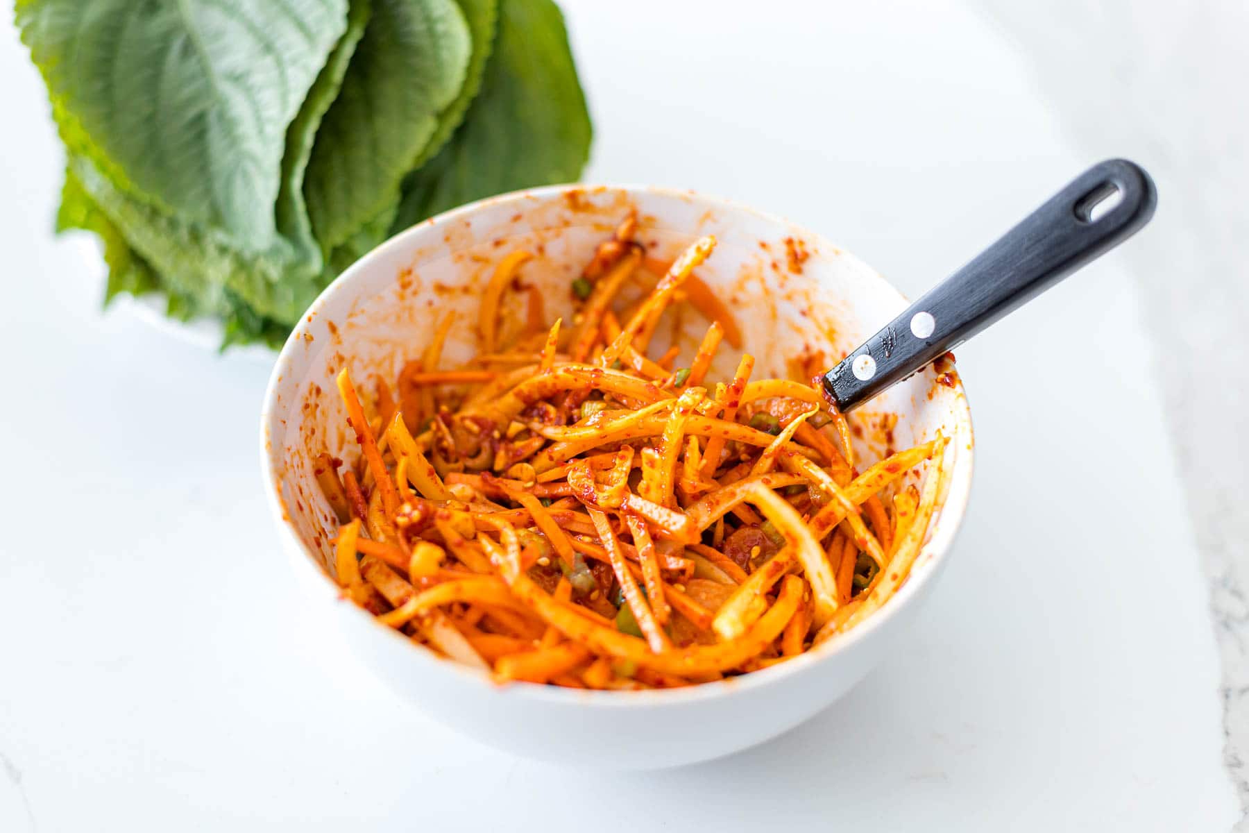 close up of Korean perilla kimchi sauce with shredded carrots, onions, and red pepper