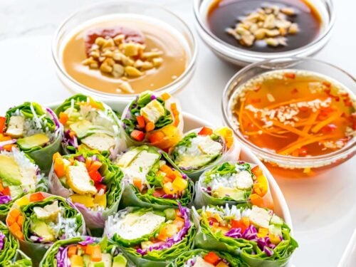 three spring roll sauces next to a plate of spring rolls