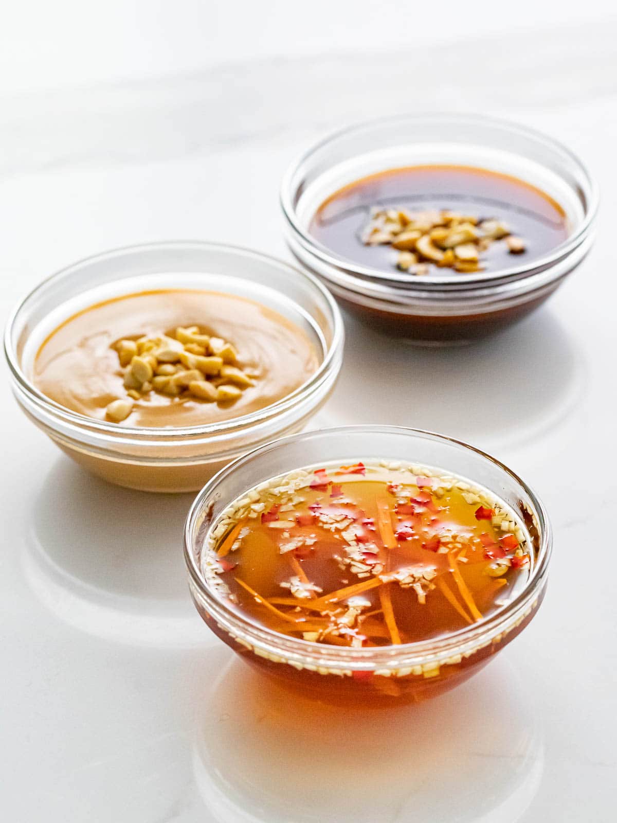 three bowls of spring roll sauces including peanut, hoisin, and fish sauce