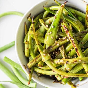 close up of stir fried garlic scapes in a white bowl