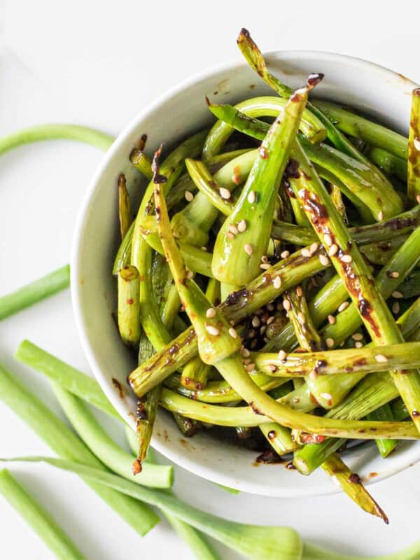close up of stir fried garlic scapes in a white bowl