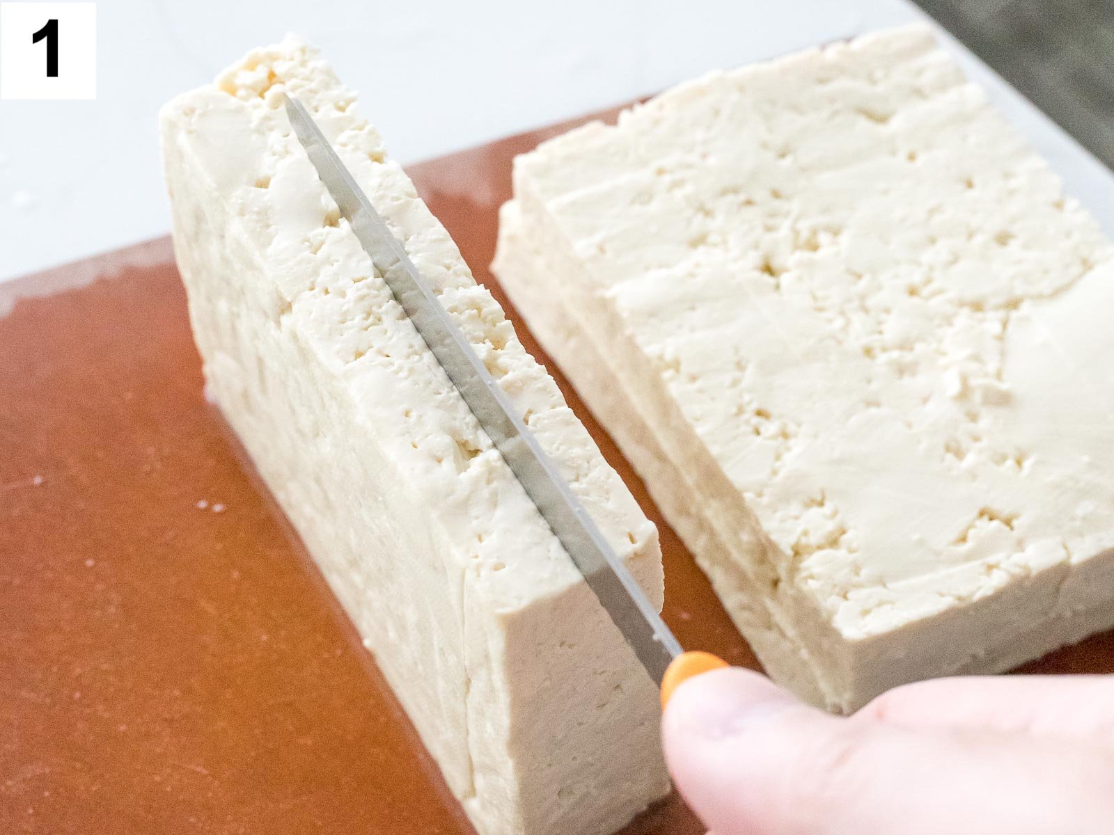 close up of tofu being cut with a knife