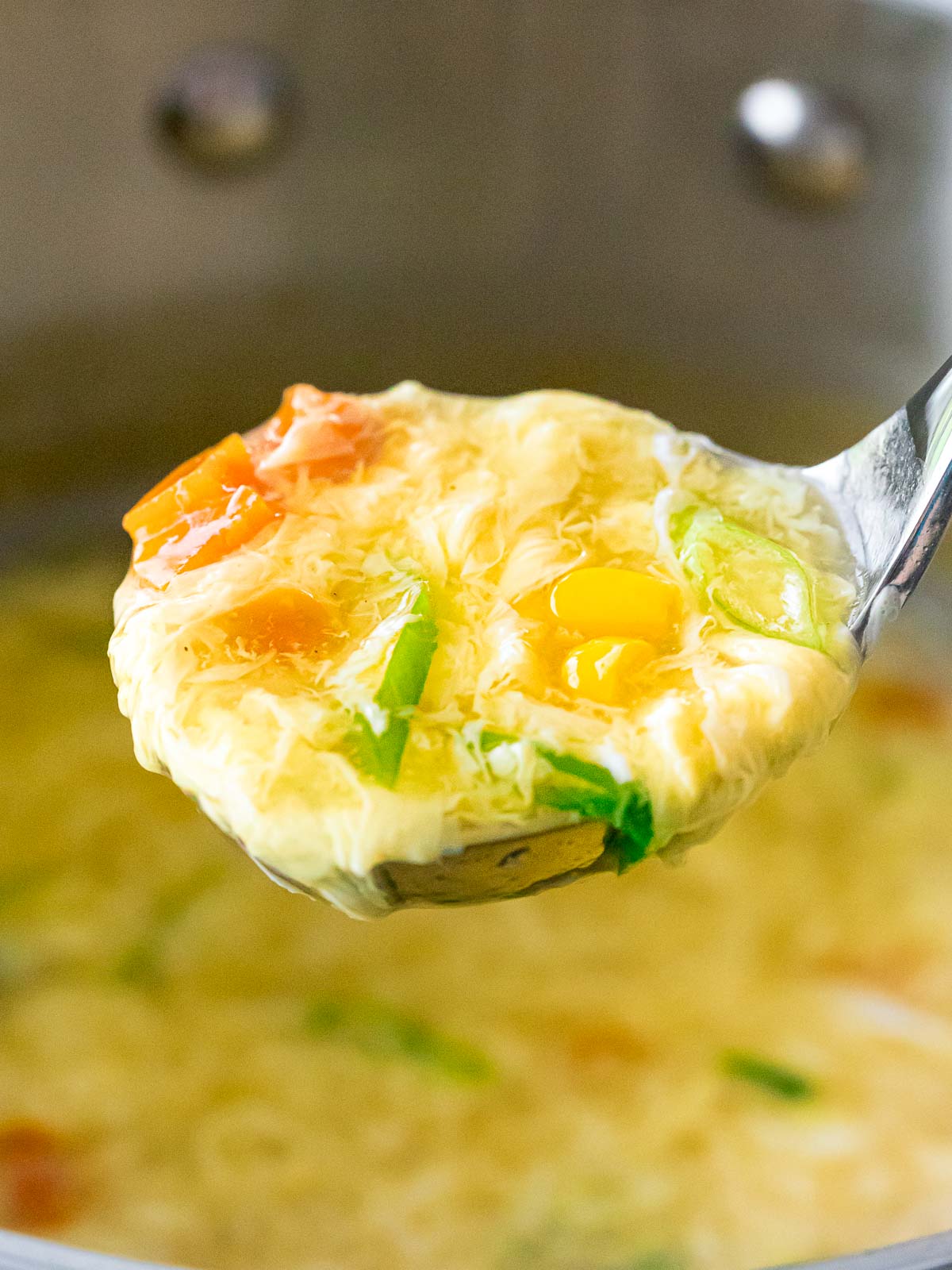 ladle full of authentic egg drop soup with corn and carrots