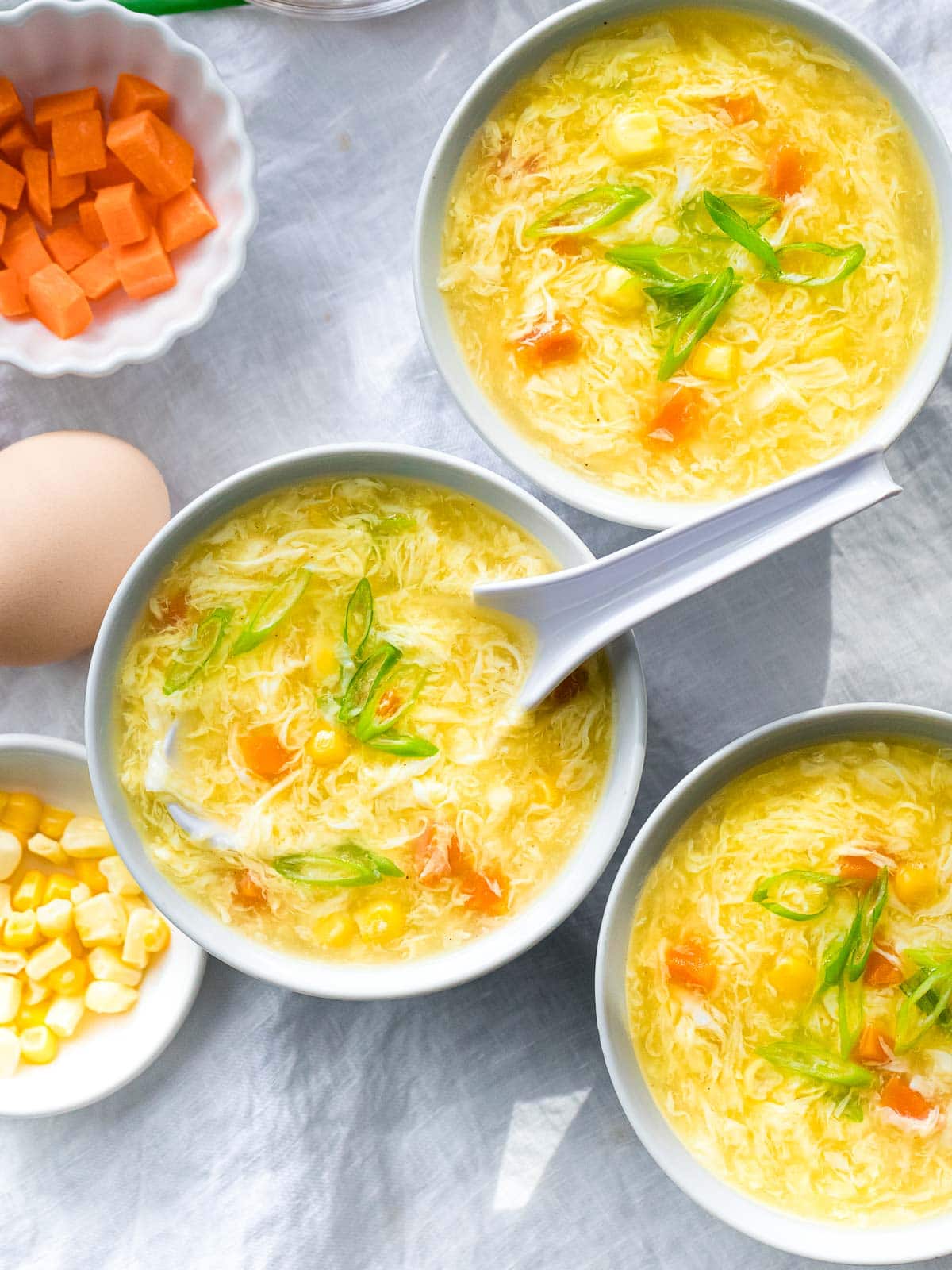three bowls of authentic egg drop soup with corn and carrots
