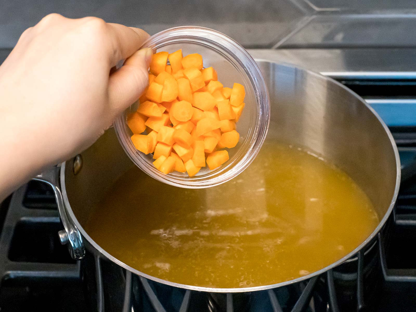 diced carrots being added to chicken stock