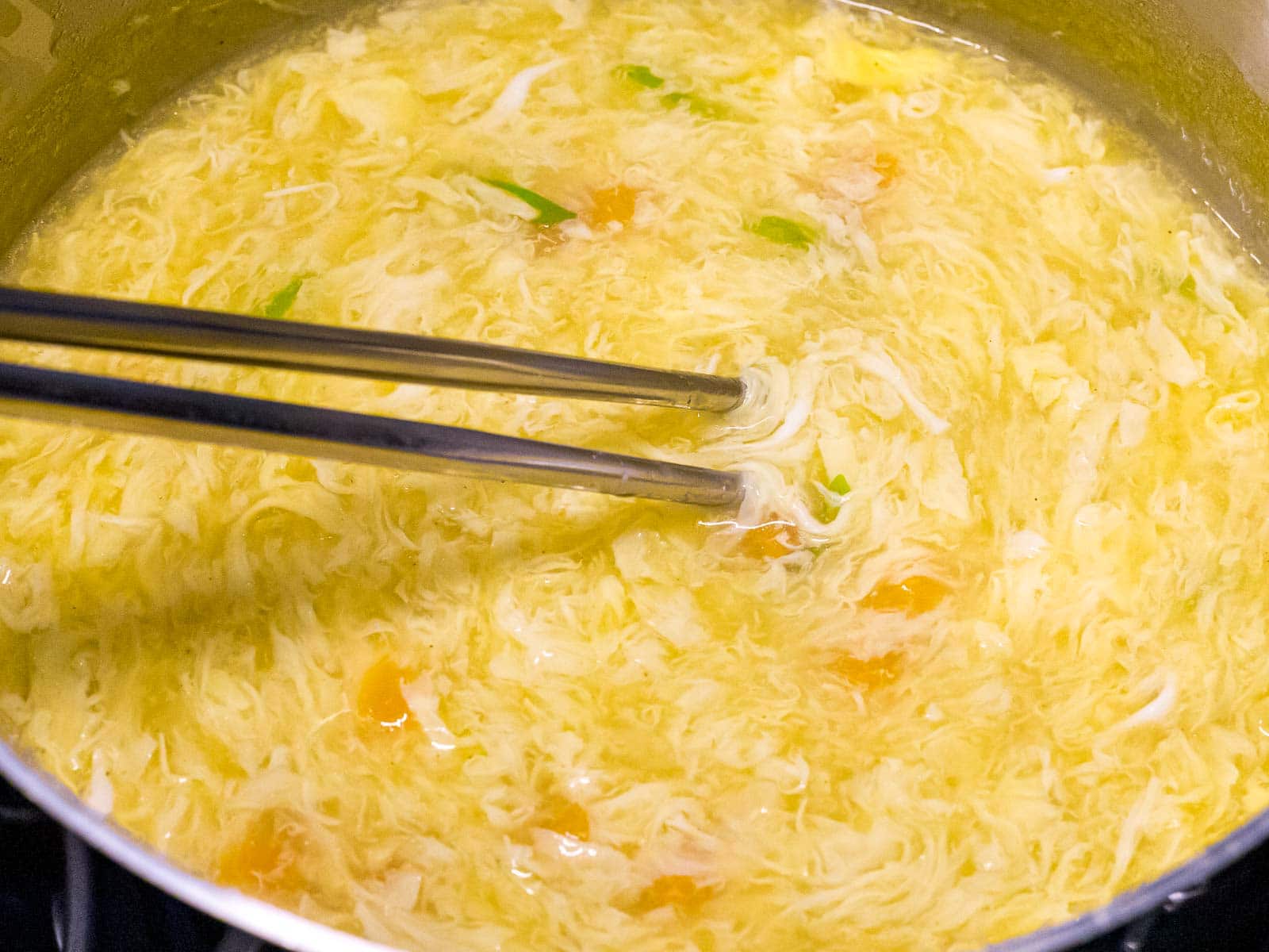 egg drop soup being stirred with chopsticks in a pot