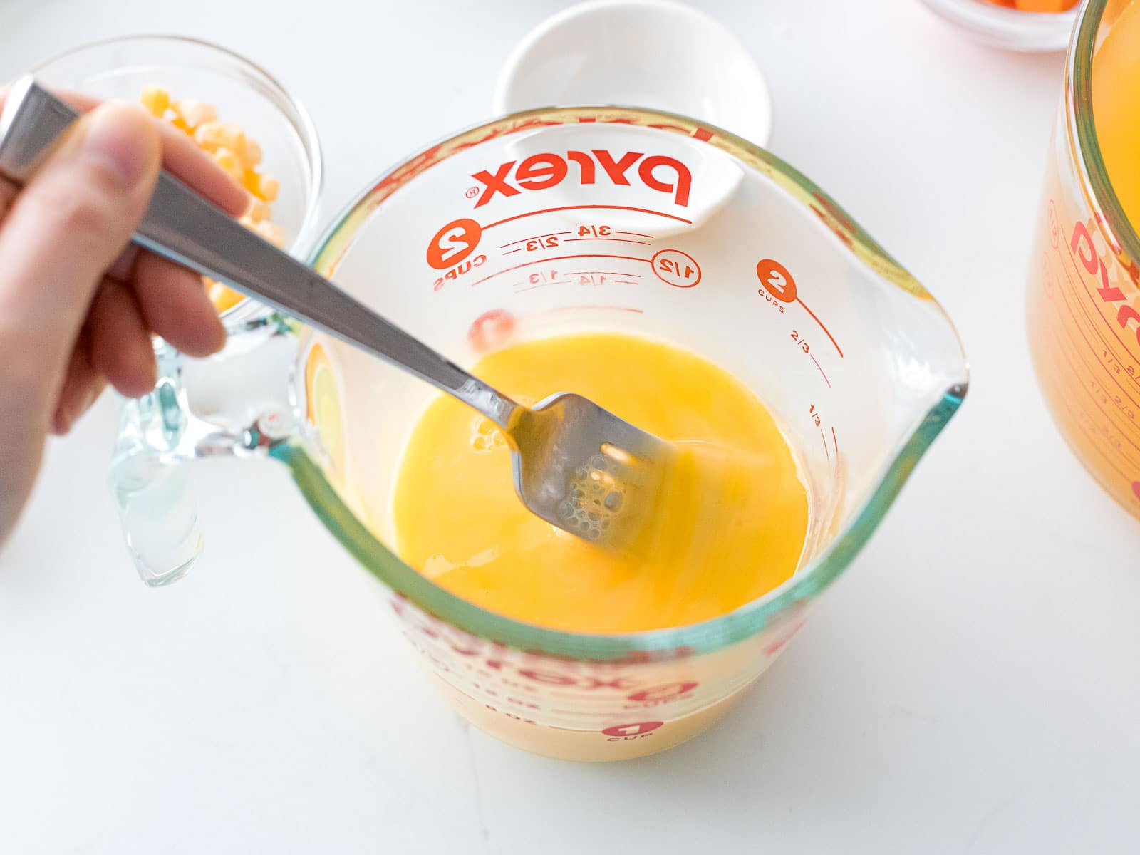 eggs being beaten in a measuring cup with a fork