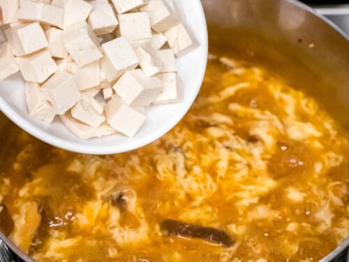 tofu being added to hot and sour soup