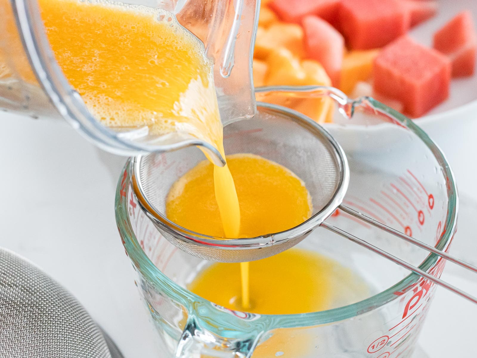 mango juice poured into a strainer