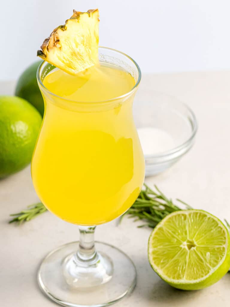 pineapple agua fresca in a glass next to lime