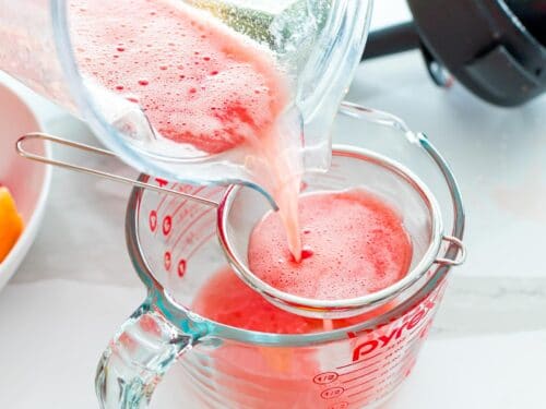 pouring watermelon juice through a strainer