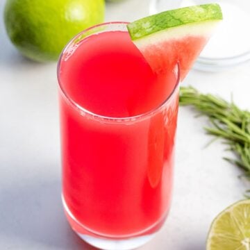 watermelon agua fresca in a glass cup with lime and herbs