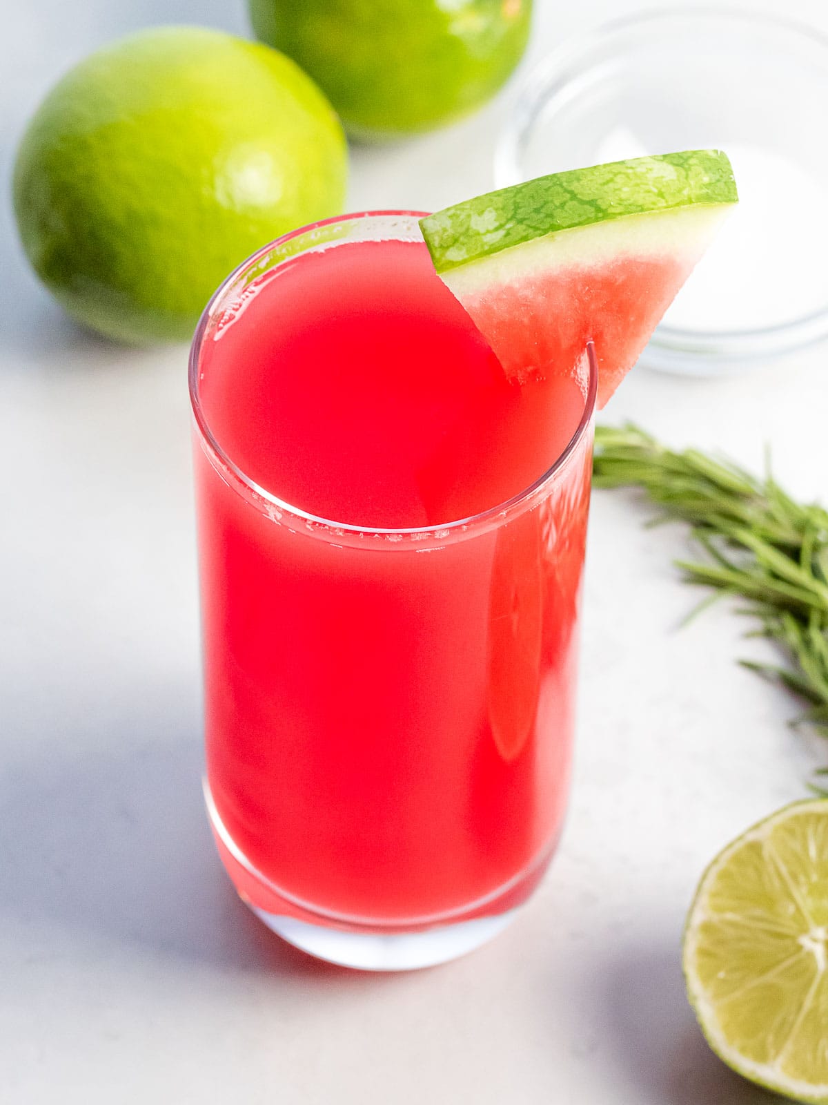 watermelon agua fresca in a glass cup with lime and herbs