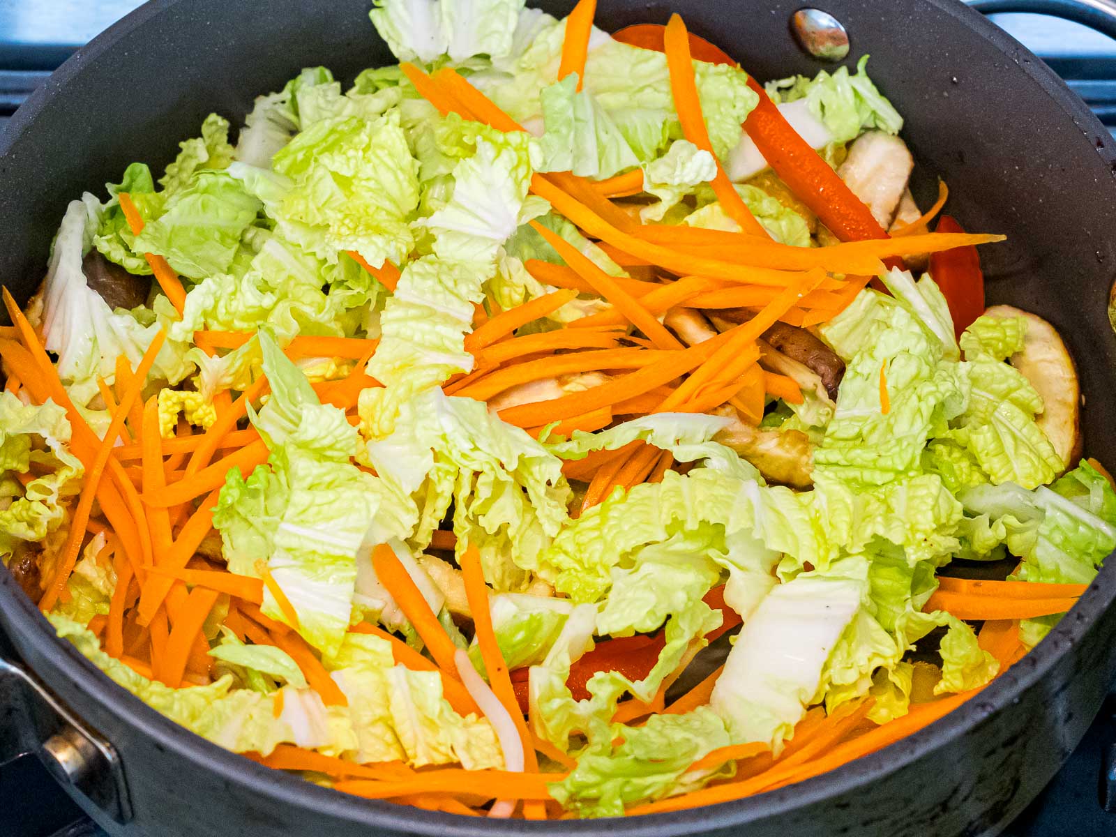 cabbage, carrots, and other vegetables stir fried in a pan