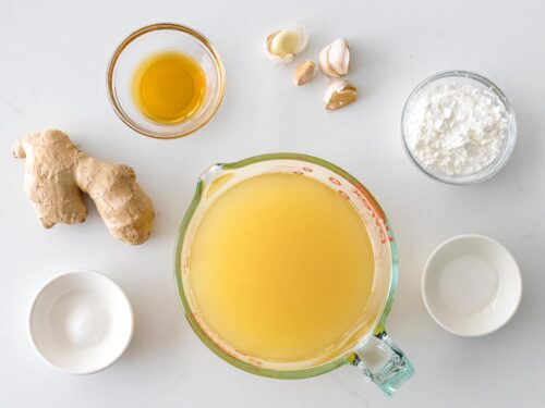 Chinese white sauce ingredients in glass bowls including chicken stock, ginger, and garlic