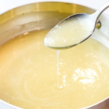 Chinese white sauce poured off a spoon into a pot