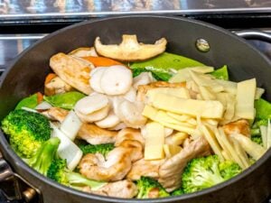 chicken, mushrooms, bamboo shoots, water chestnuts stir frying in a pan