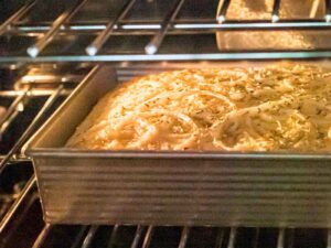 focaccia bread topped with sliced onions baking in the oven