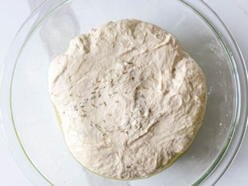 focaccia dough in a glass bowl after mixing the ingredients together