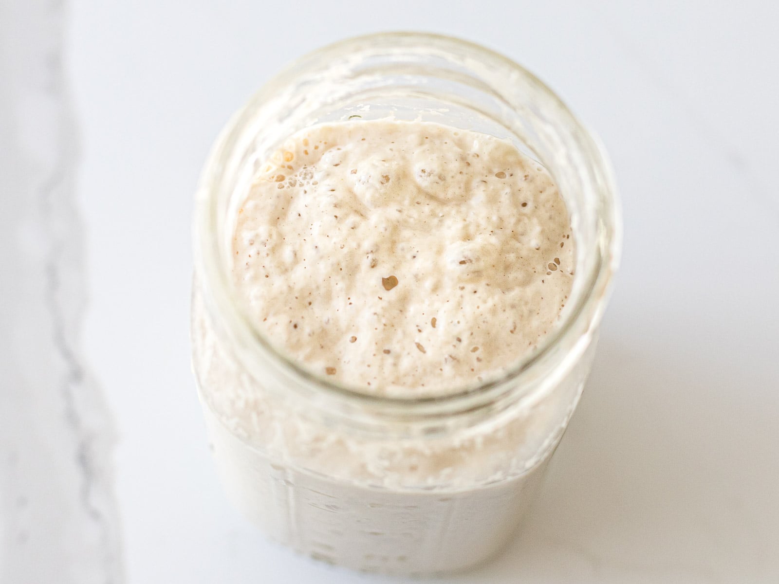 top view of an active sourdough starter in a glass jar after feeding