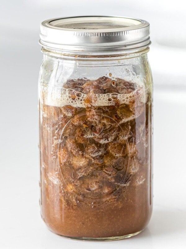 raisin yeast water with bubbles and foam in a glass mason jar with a lid