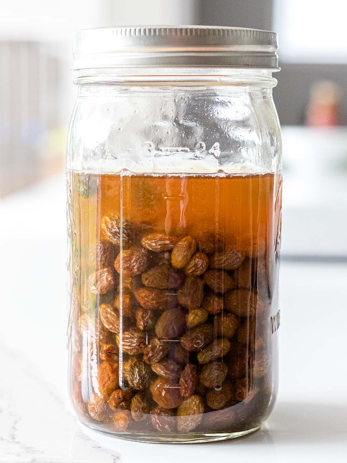 raisin yeast water in a mason glass jar on a white counter top