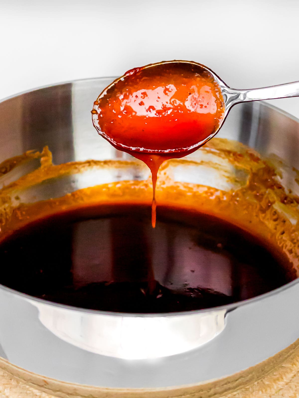 sweet gochujang sauce dripping off a spoon into a pot