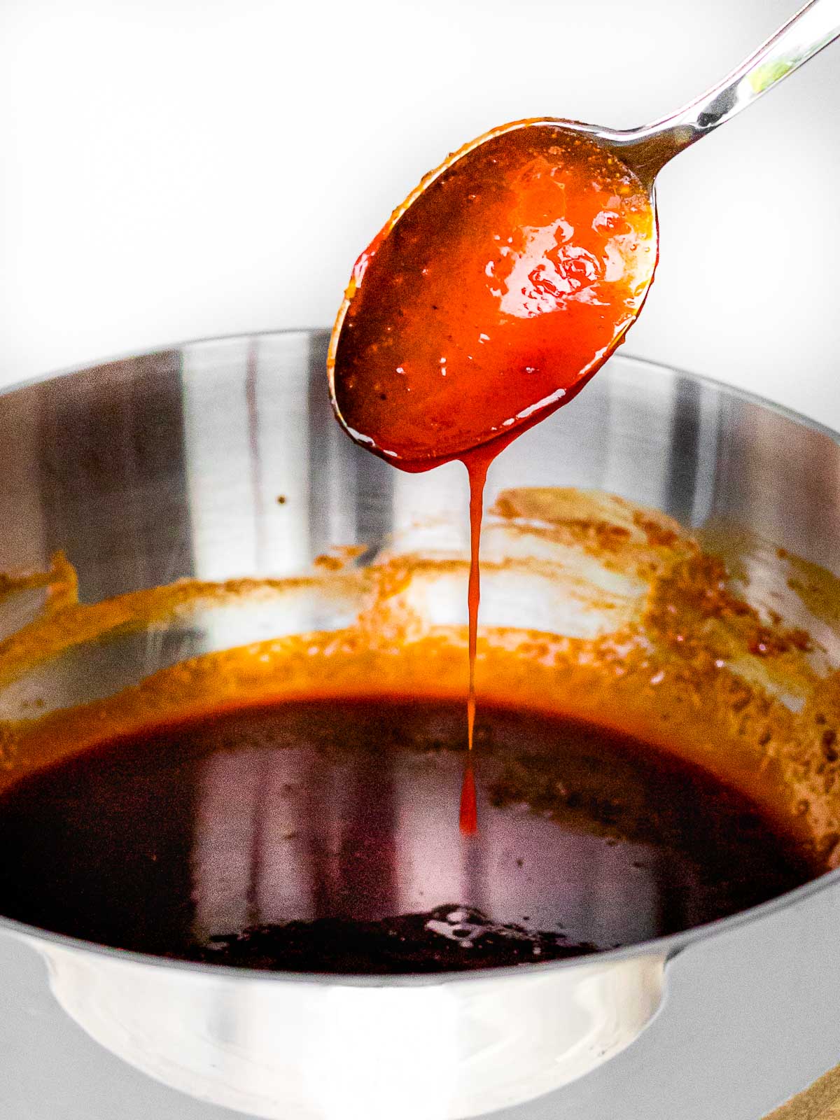 sweet and spicy gochujang sauce dripping off of a spoon into a pot