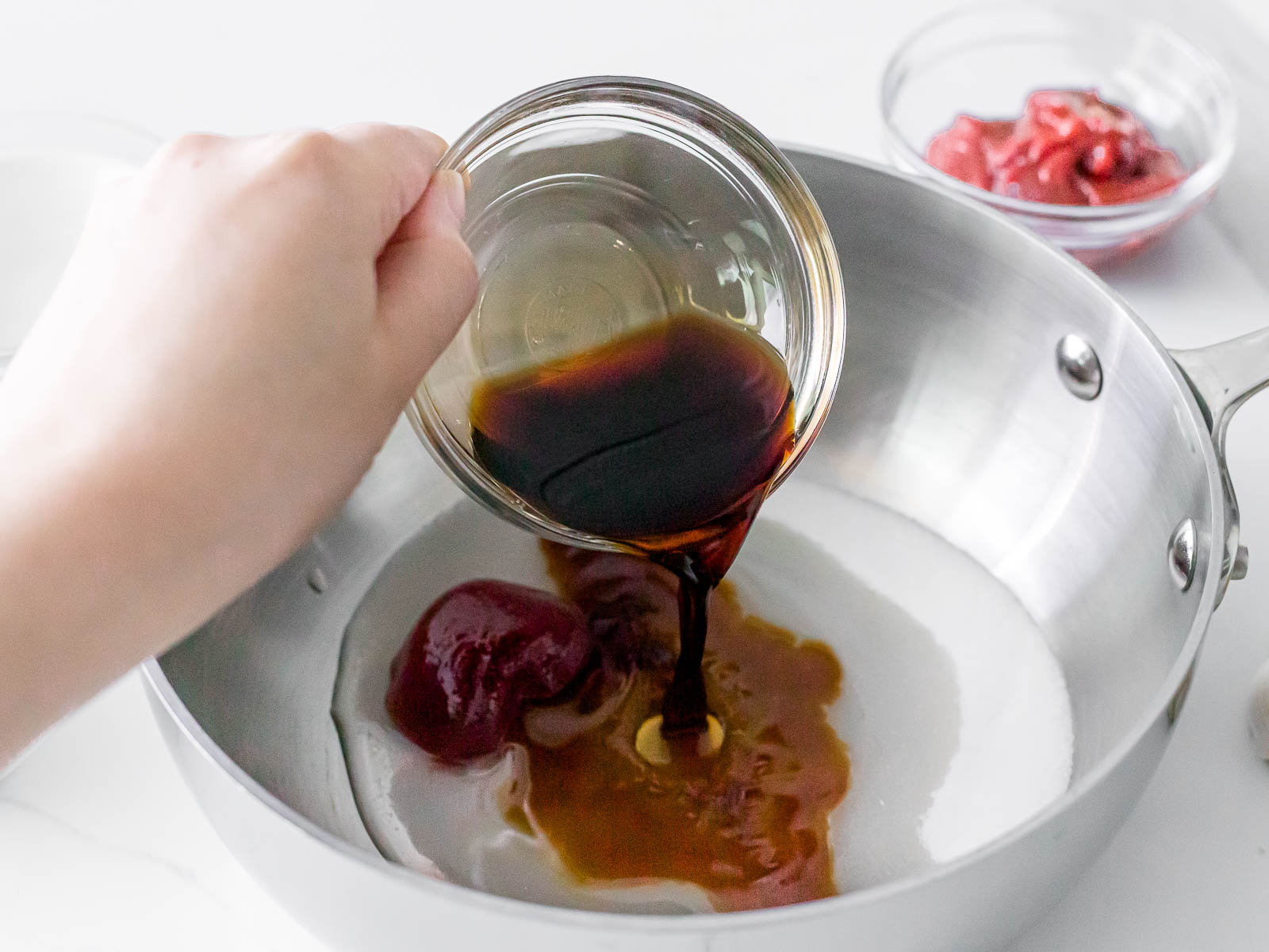 adding soy sauce to a pot with gochujang and sugar