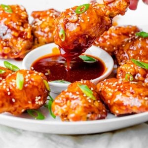 close up of crunchy Korean fried chicken covered and dipped in a gochujang yangyeom sauce
