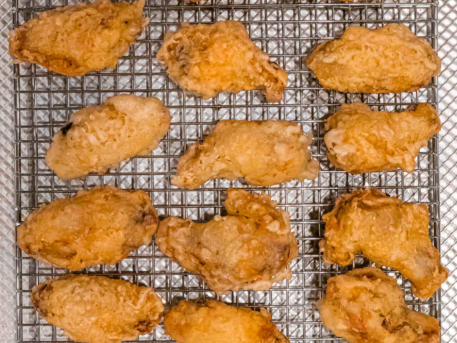 plain Korean fried chicken wings after being double fried resting on a metal cooling rack