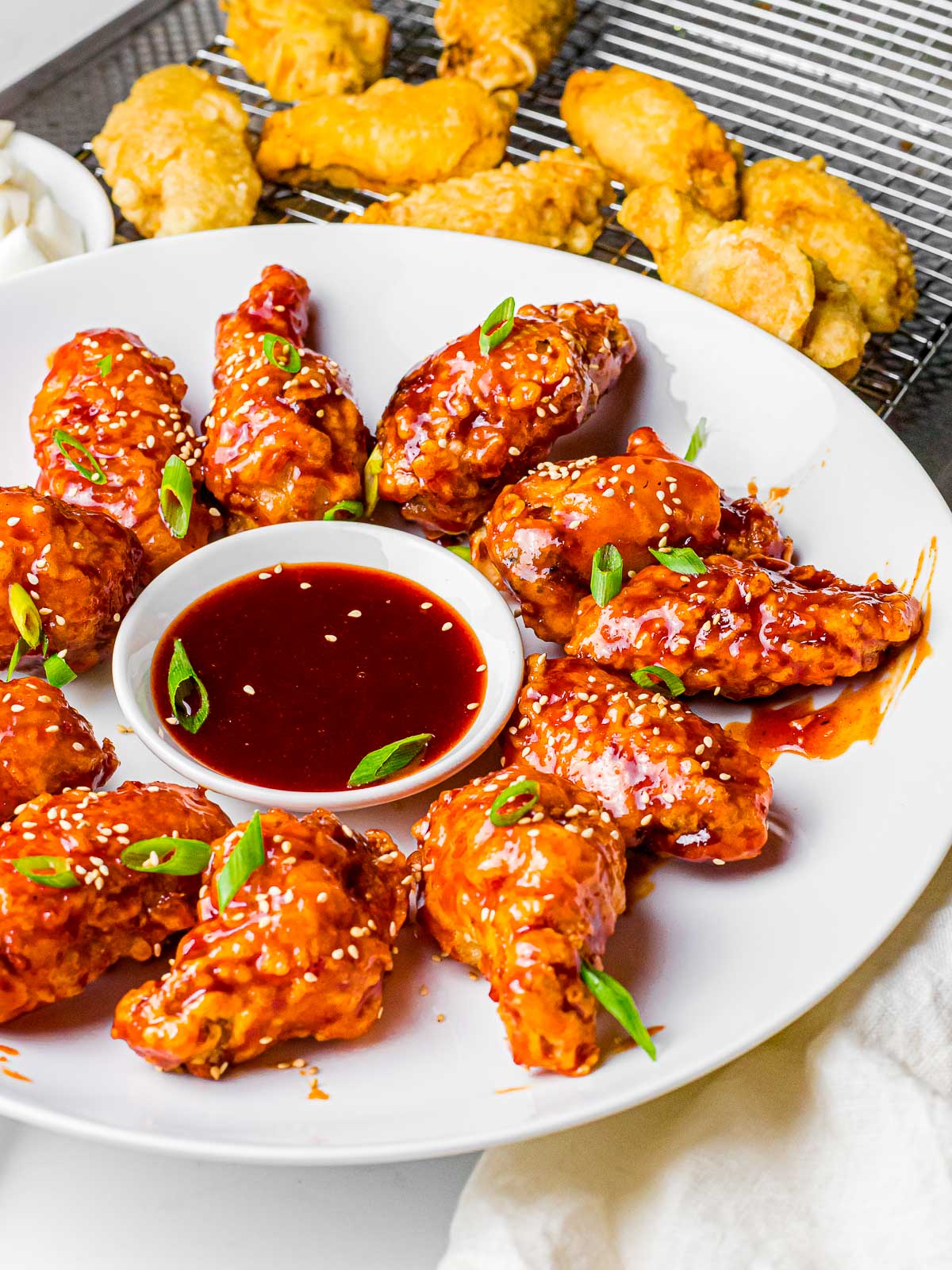 a plate of yangnyeom chicken surrounding gochujang dipping next to plain chicken wings