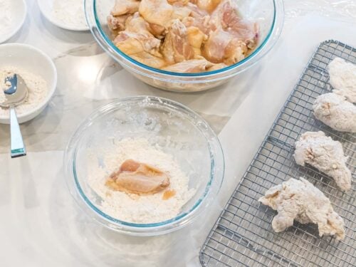 raw chicken wings being battered in flour and laying on a cooking rack