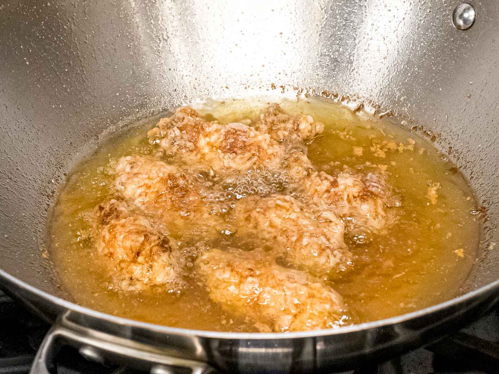 battered chicken wings double frying in oil in a metal wok
