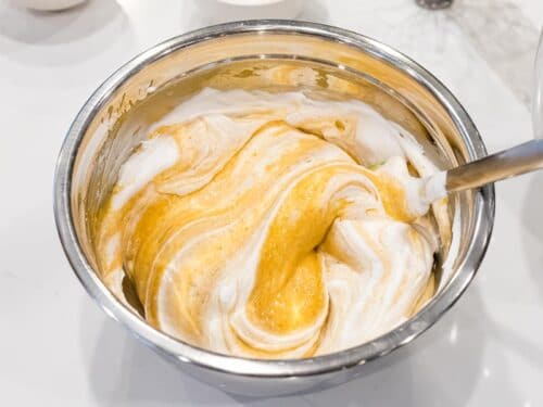pumpkin cake batter mixed with egg white meringue in a metal mixing bowl