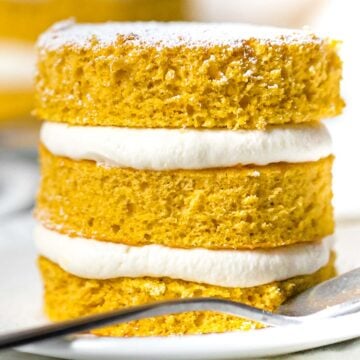 close up of mini pumpkin layer cake with cream cheese frosting on a white plate
