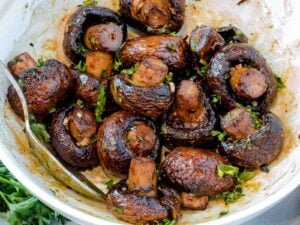 oven baked mushrooms with parsley in a white bowl with a spoon