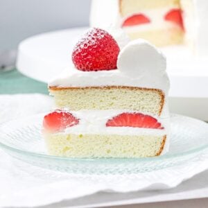 close up of slice of Japanese strawberry shortcake with whipped cream frosting on a glass plate