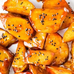 close up of Korean candied sweet potatoes with golden brown caramel coating and black sesame seeds