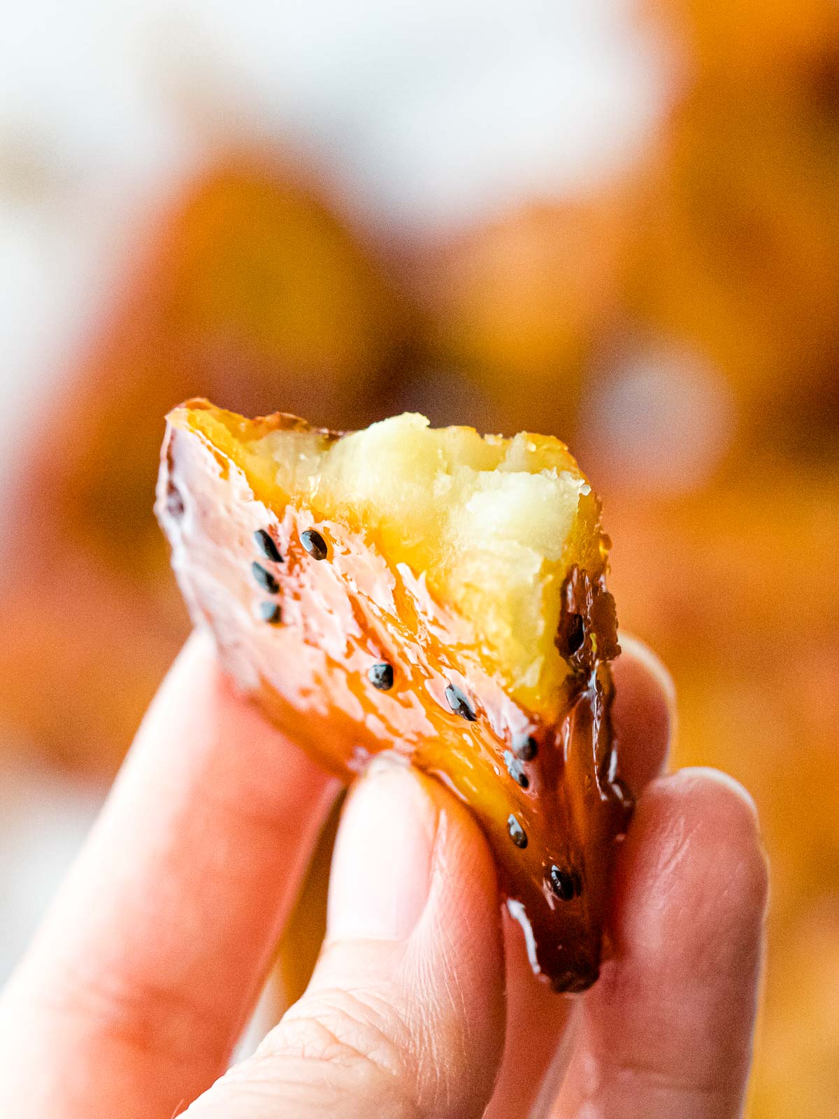hand holding Korean caramelized sweet potato showing fluffy inside with hard candy shell