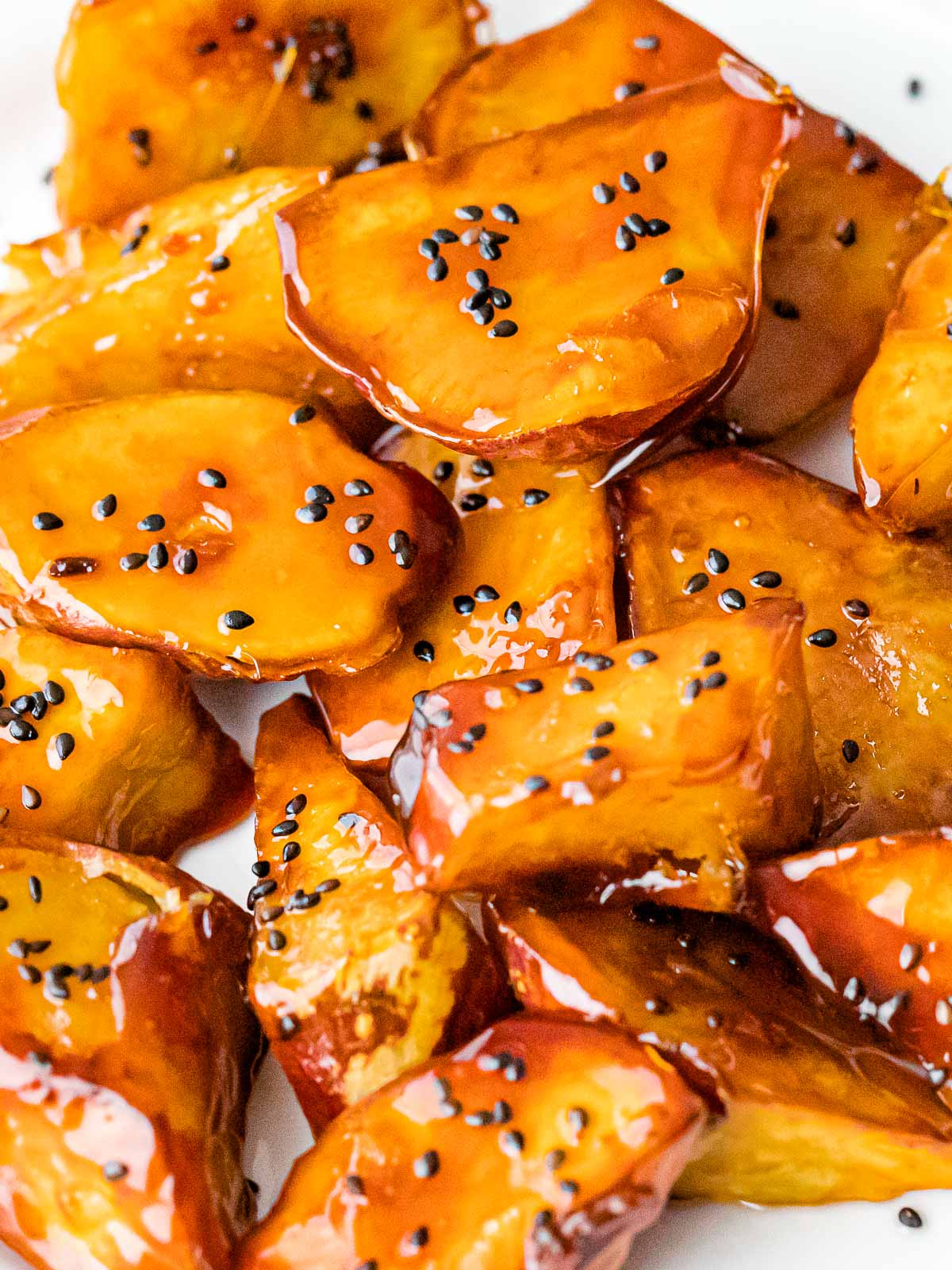 Korean candied sweet potatoes, goguma mattang, covered in golden brown caramel candy and sprinkled with black sesame seeds