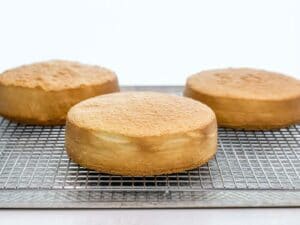 three golden brown and fluffy sponge cakes cooling on a wire rack