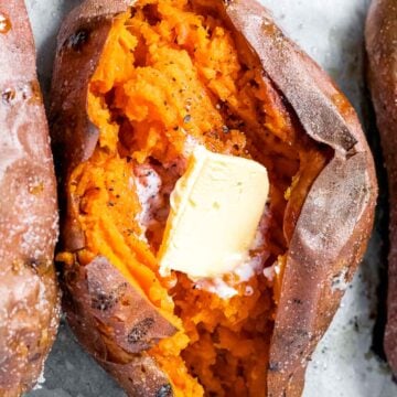 perfect baked sweet potato cut open to reveal soft flesh with a pad of butter on top