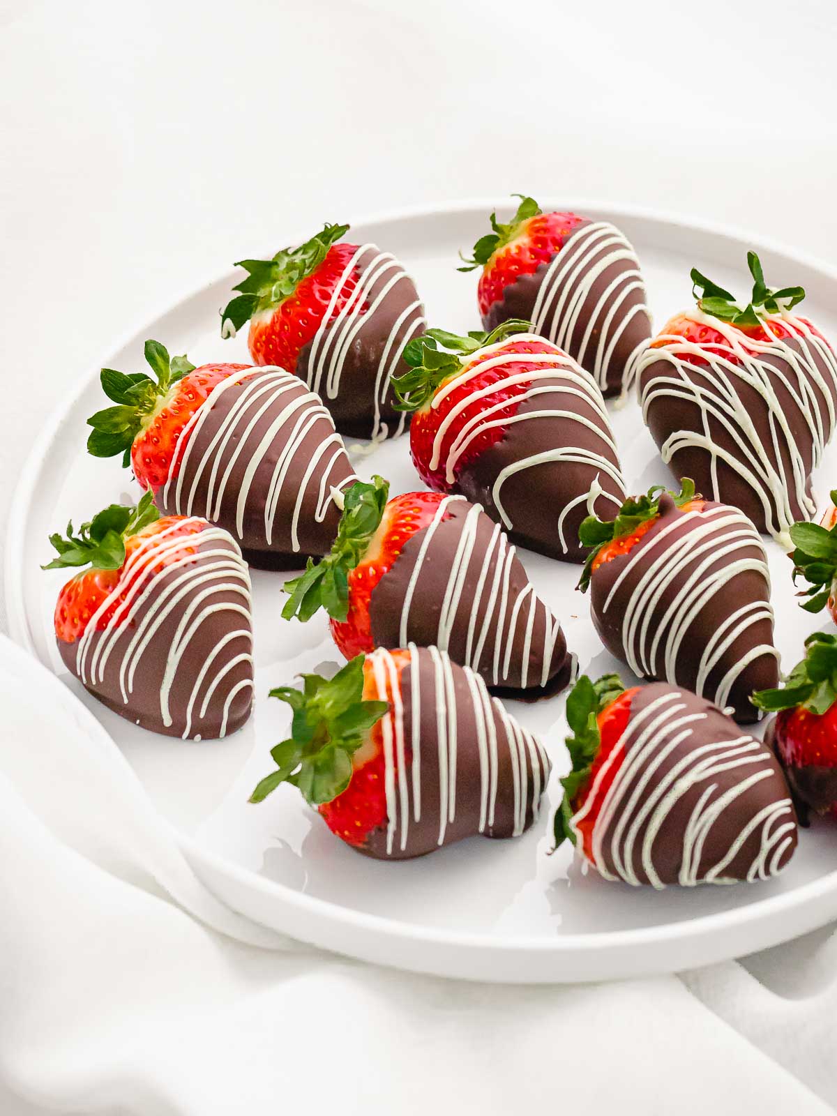 chocolate covered strawberries with white chocolate decoration on a white plate